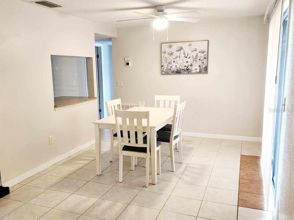 A dining room with a white table, four chairs, tile flooring, and a ceiling fan — 4022 BEAVER LANE UNIT 800D, PORT CHARLOTTE, FL