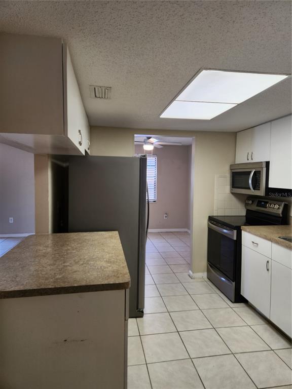 A kitchen features white cabinets, stainless steel appliances, a laminate countertop, and tile flooring — 4022 BEAVER LANE UNIT 800D, PORT CHARLOTTE, FL