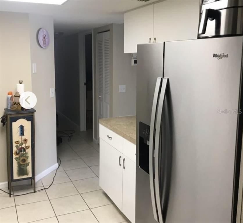 A kitchen features white cabinets, a stainless steel refrigerator, and light-colored tile flooring — 4022 BEAVER LANE UNIT 800D, PORT CHARLOTTE, FL