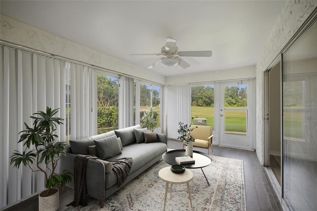 A sunroom with a gray sofa, coffee tables, and a view of a grassy field — 3647 TEESIDE DRIVE, NEW PORT RICHEY, FL