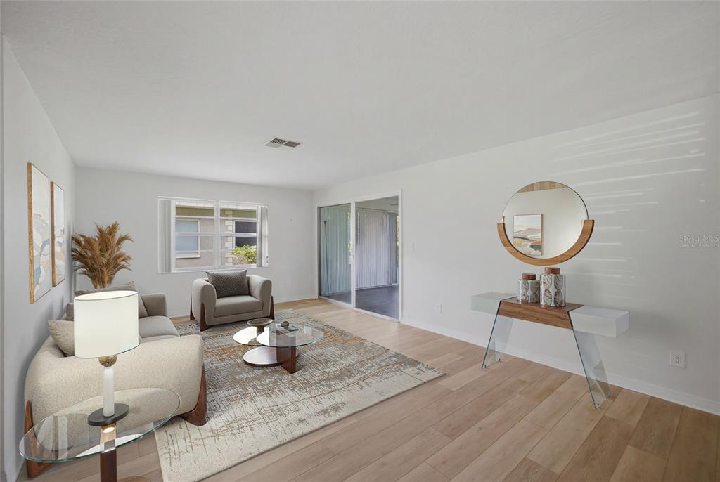 A living room with light wood floors, a glass coffee table, and a modern console table — 3647 TEESIDE DRIVE, NEW PORT RICHEY, FL