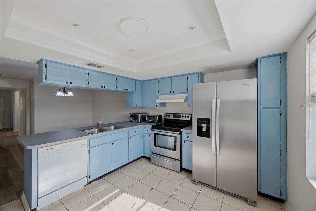A kitchen with light blue cabinets, stainless steel appliances, and light-colored tile flooring — 3647 TEESIDE DRIVE, NEW PORT RICHEY, FL