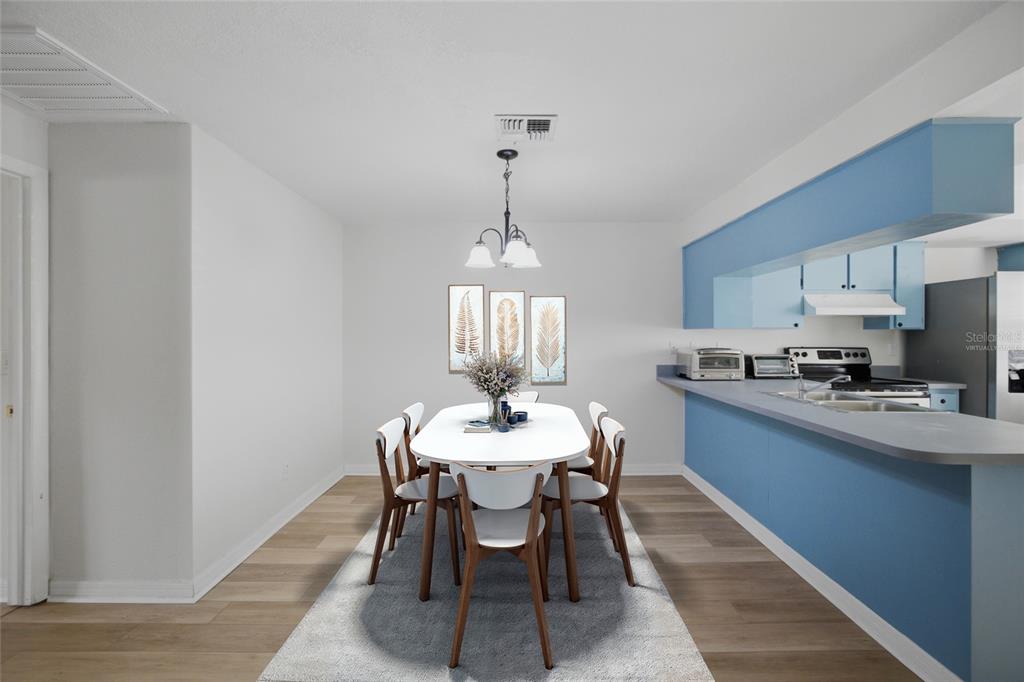 A dining area with a white table, six chairs, and blue kitchen cabinetry — 3647 TEESIDE DRIVE, NEW PORT RICHEY, FL