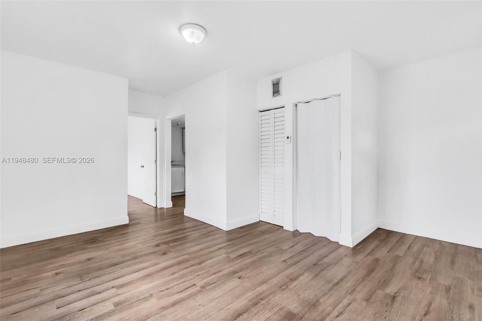 A room with white walls, wood-look flooring, and two closet doors — 8329 NW 5th Ave # 1, Miami FL 33150, MIAMI, FL