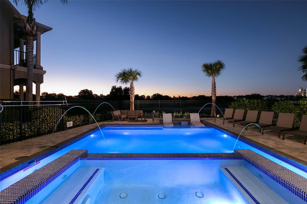 A swimming pool and hot tub are illuminated at dusk with palm trees in the background — 1514 COROLLA COURT, REUNION, FL