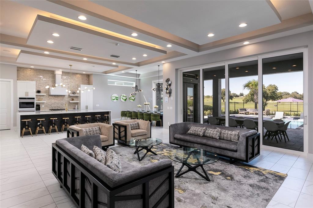 An open-concept living area features a modern kitchen, gray sofas, and sliding doors to a patio — 1514 COROLLA COURT, REUNION, FL