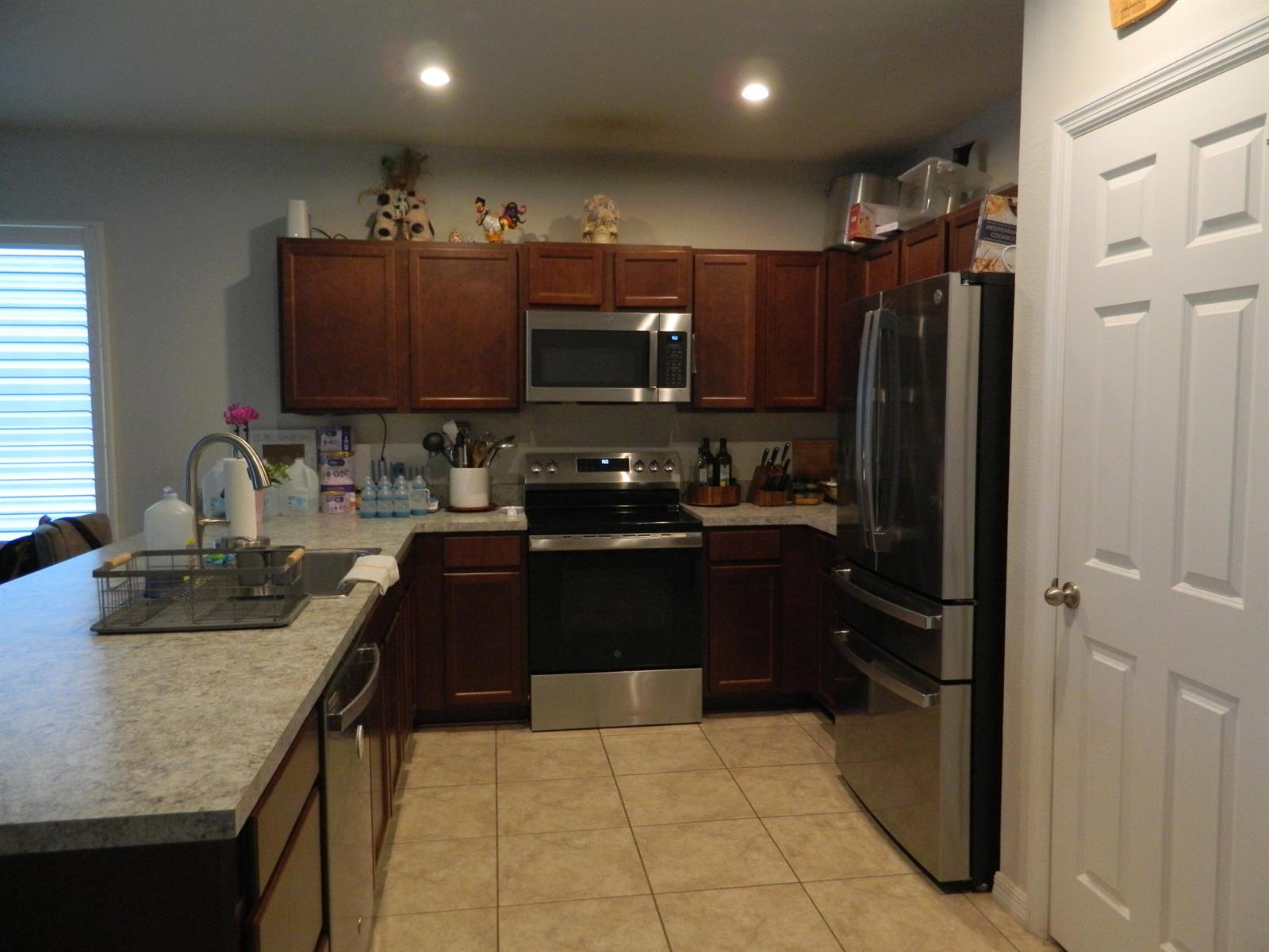 A kitchen features dark wood cabinets, stainless steel appliances, and light-colored countertops — 3345 Liberty Square Way # 101, Fort Pierce FL 34982, FORT PIERCE, FL