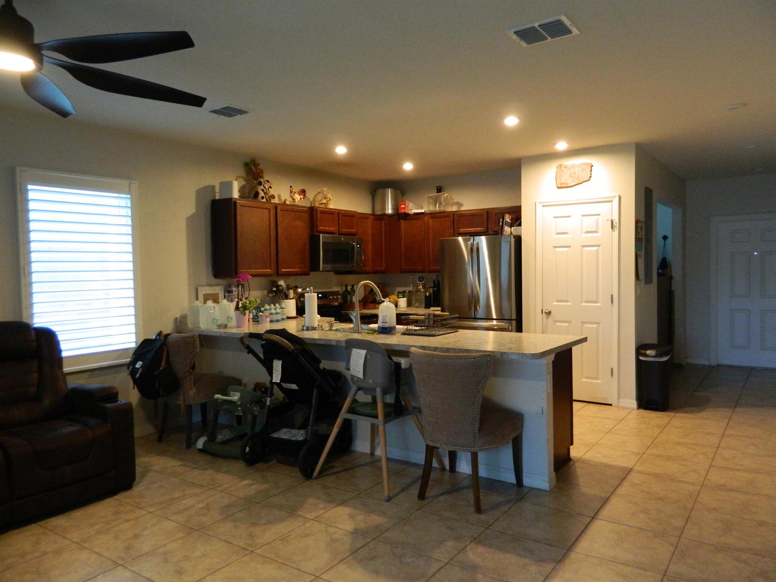 A kitchen features dark wood cabinets, stainless steel appliances, a breakfast bar, and tile flooring — 3345 Liberty Square Way # 101, Fort Pierce FL 34982, FORT PIERCE, FL
