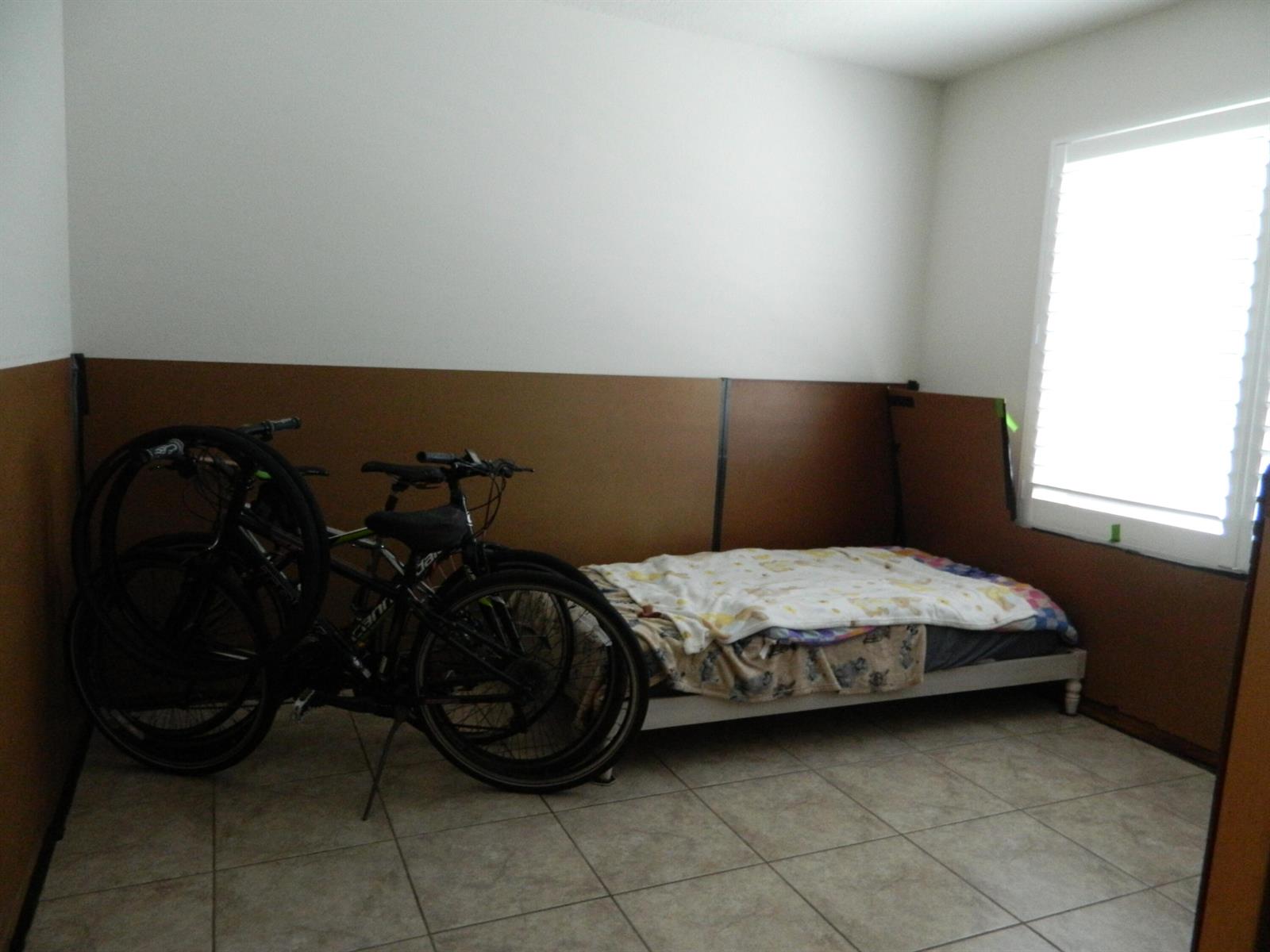 A bedroom with tile flooring, a single bed, and two bicycles parked against the wall — 3345 Liberty Square Way # 101, Fort Pierce FL 34982, FORT PIERCE, FL