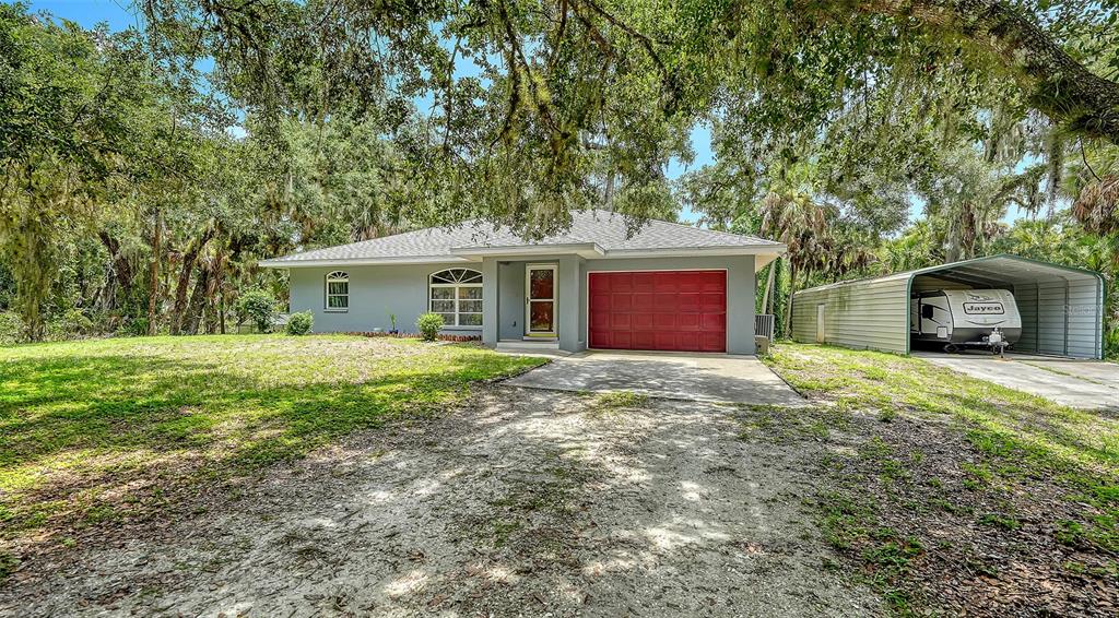 A single-story house with a red garage door and a detached metal carport — 4498 HIDDEN RIVER ROAD, SARASOTA, FL