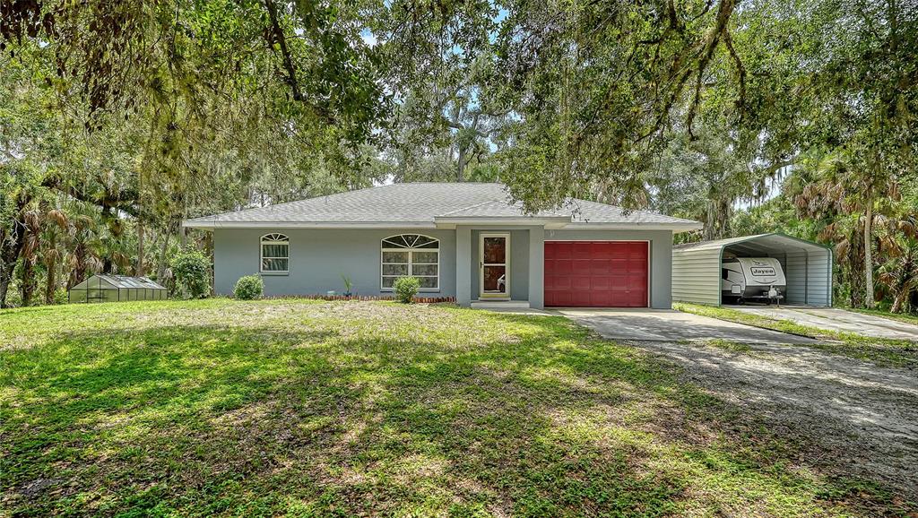 A gray single-story house with a red garage door and a metal carport for an RV — 4498 HIDDEN RIVER ROAD, SARASOTA, FL