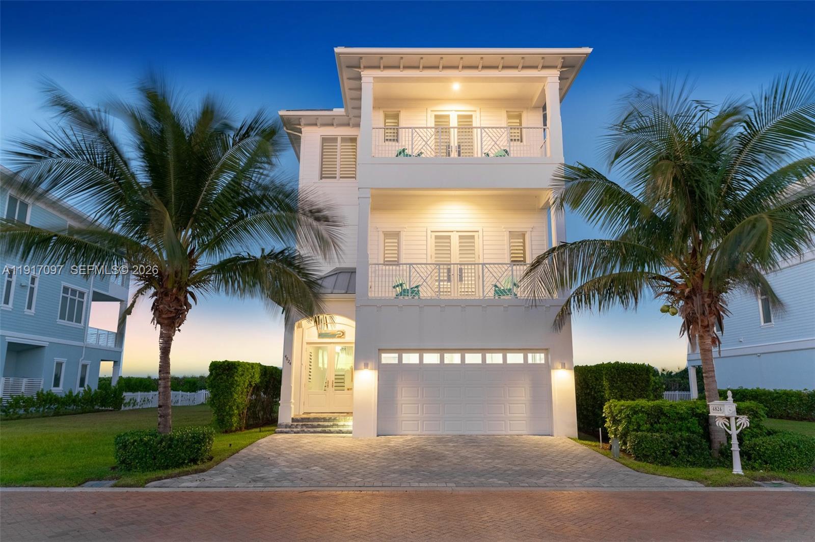 A three-story white coastal house features two stacked balconies, a garage, and palm trees — 4824 Watersong Way, Fort Pierce FL 34949, FORT PIERCE, FL