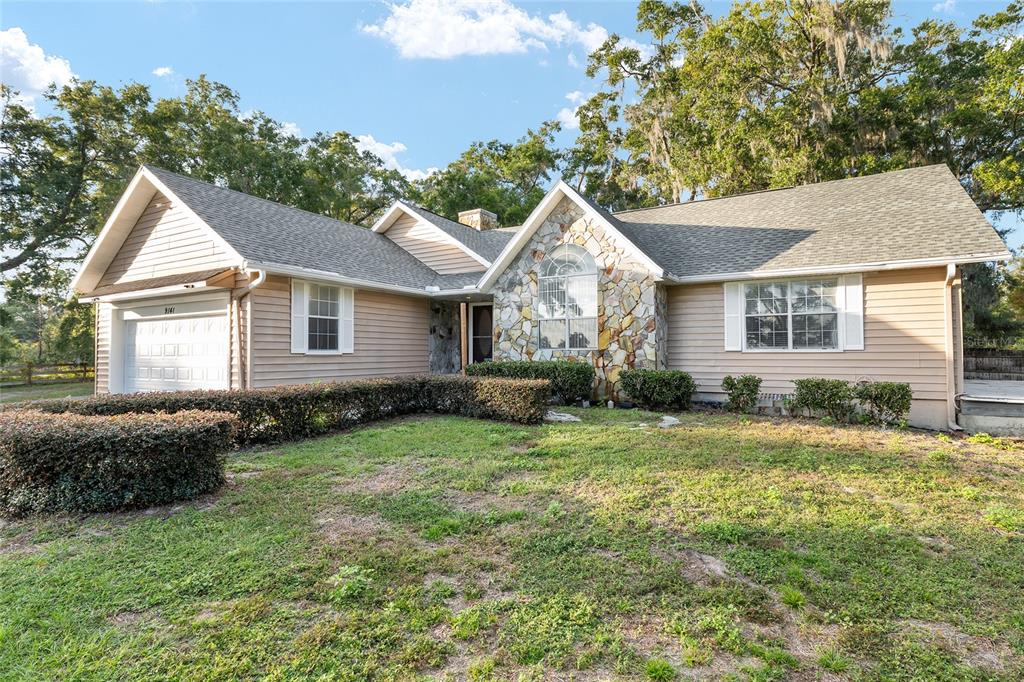 A single-story house with tan siding, a stone facade, and a front-facing garage — 9161 SW 34TH PLACE, OCALA, FL