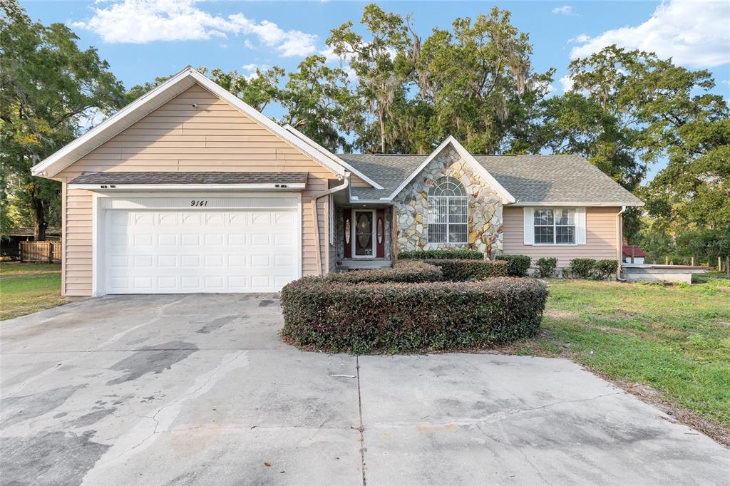A single-story house with tan siding, a stone facade, and a two-car garage — 9161 SW 34TH PLACE, OCALA, FL
