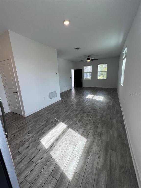 A hallway with wood-look flooring leads to a doorway, with carpeted stairs on the right — 2817 CAMDEN WAY, DAVENPORT, FL