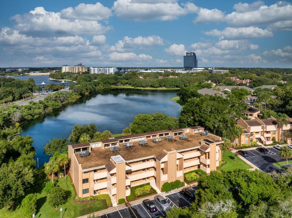 An aerial view of a multi-story apartment building situated next to a lake and trees — 510 CRANES WAY UNIT 206, ALTAMONTE SPRINGS, FL