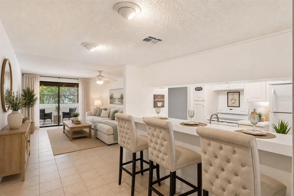 An open-concept living room and kitchen featuring a breakfast bar with tufted stools — 510 CRANES WAY UNIT 206, ALTAMONTE SPRINGS, FL