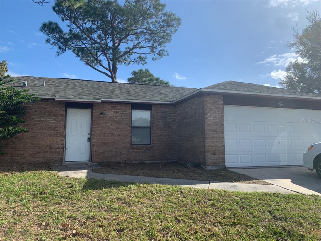 A single-story brick house features a white front door, a garage, and a shingled roof — 1395 COX AVENUE NW, PALM BAY, FL