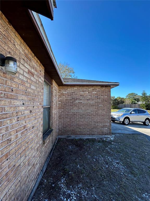 A side view of a brick house exterior with a window and a parked car — 1395 COX AVENUE NW, PALM BAY, FL