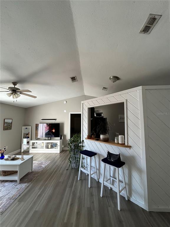 A living room features light wood-look flooring, a white breakfast bar, and a ceiling fan — 1395 COX AVENUE NW, PALM BAY, FL