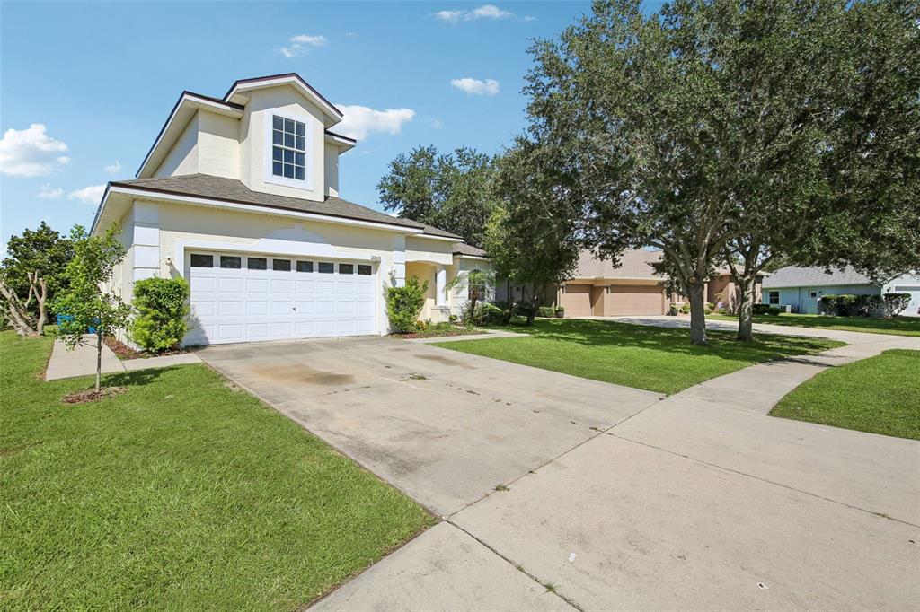A two-story house with a white garage, beige siding, and a concrete driveway — 2265 LONG VIEW CIRCLE, BROOKSVILLE, FL