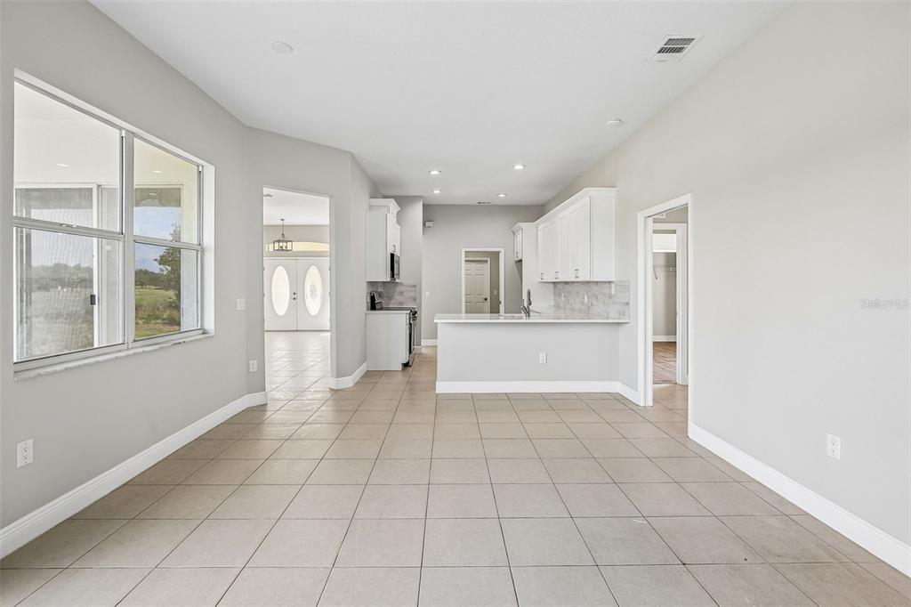 An open-concept kitchen and dining area features white cabinets, light tile floors, and large windows — 2265 LONG VIEW CIRCLE, BROOKSVILLE, FL