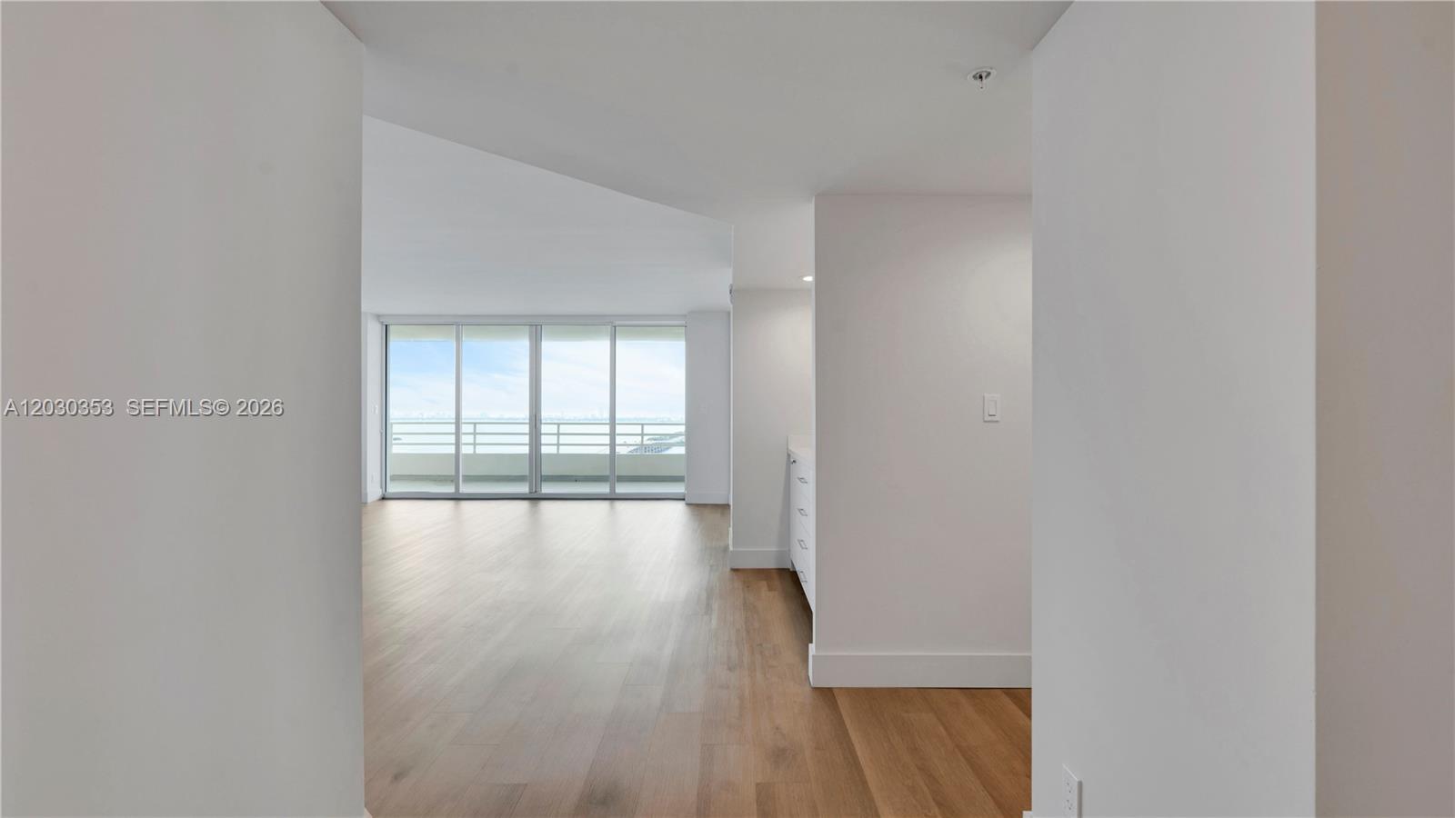 An empty room with light wood floors, white walls, and floor-to-ceiling windows overlooking water — 555 NE 34th St # 1601, Miami FL 33137, MIAMI, FL