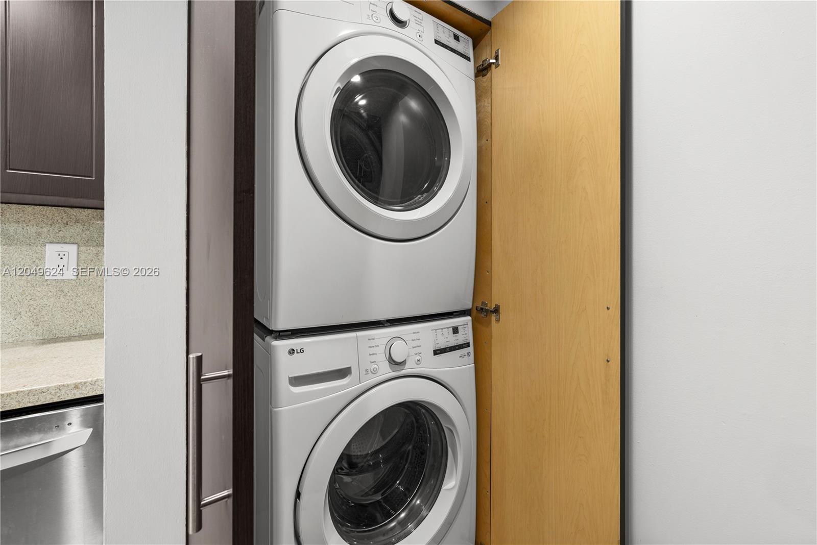 A stacked LG washer and dryer unit is housed inside a wooden cabinet — 2457 Collins Ave # 307, Miami Beach FL 33140, MIAMI BEACH, FL