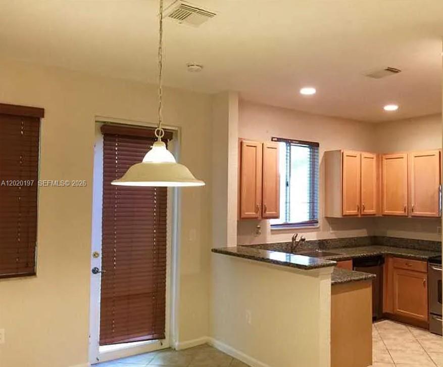 A kitchen features light wood cabinets, granite countertops, and a pendant light over the area — 21115 NW 14th Pl # 2, Miami Gardens FL 33169, MIAMI GARDENS, FL
