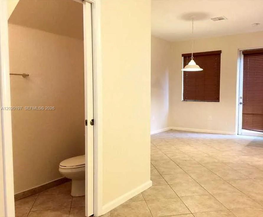 A tiled room features a small bathroom with a toilet visible through an open doorway — 21115 NW 14th Pl # 2, Miami Gardens FL 33169, MIAMI GARDENS, FL