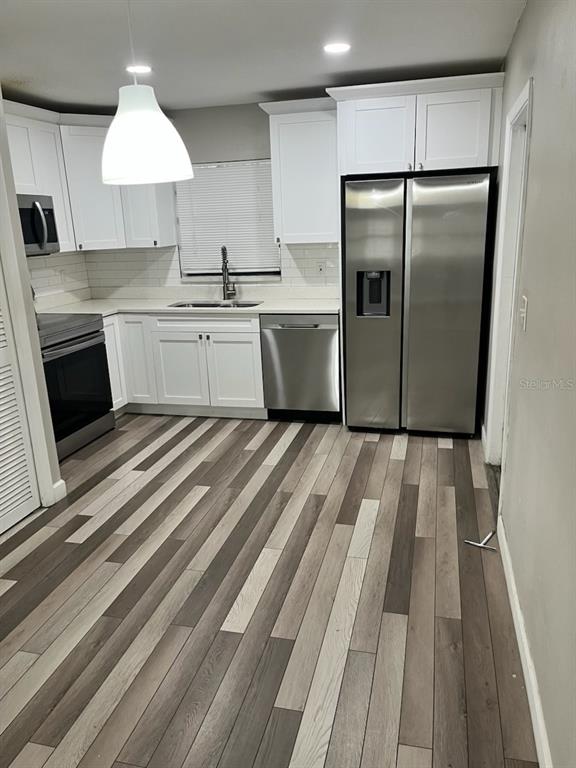 A kitchen features white cabinets, stainless steel appliances, and multi-toned wood-look flooring — 3810 W CLEVELAND STREET UNIT B, TAMPA, FL