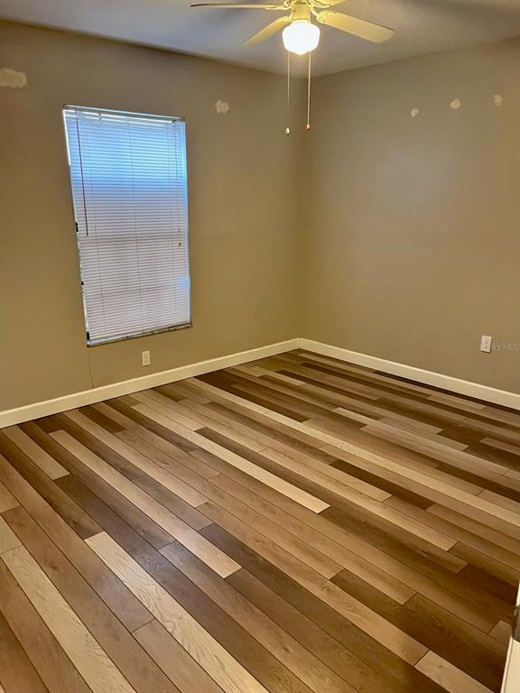 An empty bedroom features light brown walls, a ceiling fan, and wood-look plank flooring — 3810 W CLEVELAND STREET UNIT B, TAMPA, FL