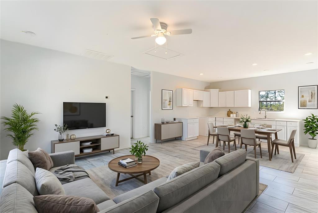 An open-concept living and dining area features light wood-look tile floors and white cabinetry — 1403 BITTERSWEET STREET, LAKE PLACID, FL