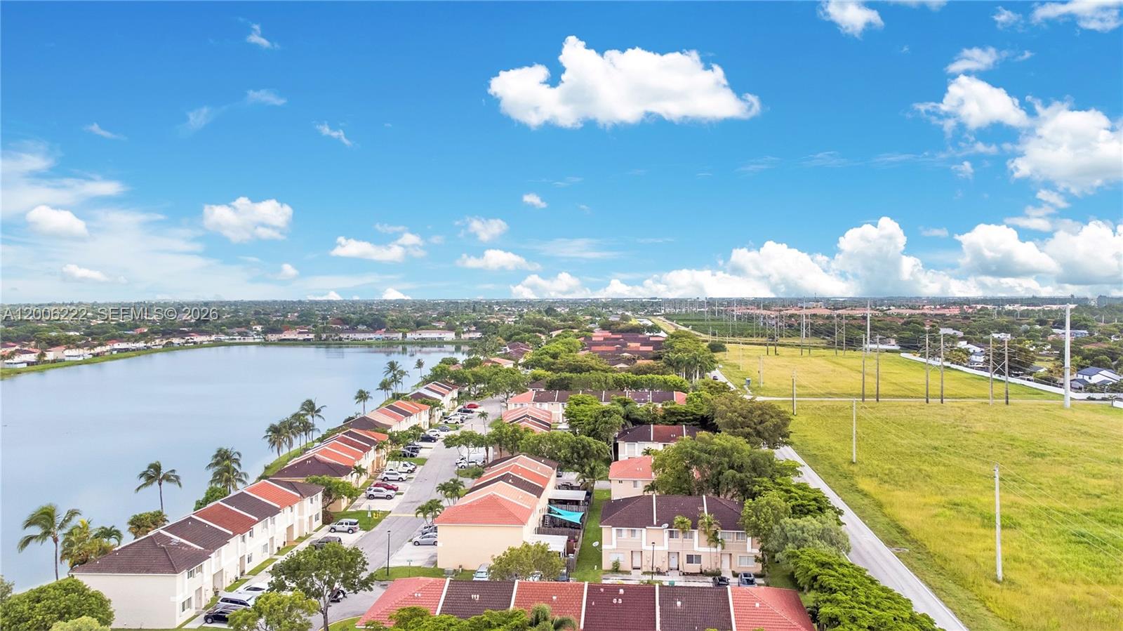An aerial view shows townhouses situated beside a lake and a large open field — 13909 SW 178th St # 1, Miami FL 33177, MIAMI, FL