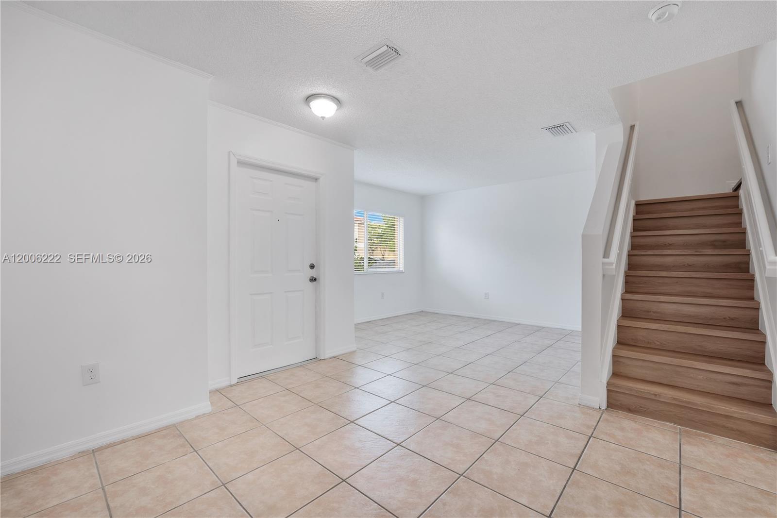 This room features tile flooring, a white front door, and a wooden staircase — 13909 SW 178th St # 1, Miami FL 33177, MIAMI, FL
