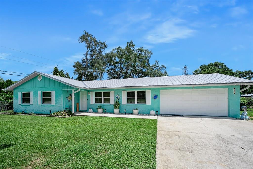 A single-story turquoise house with a white garage door and a metal roof — 311 ACACIA DRIVE, PORT ORANGE, FL