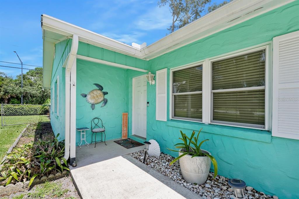 The exterior of a turquoise house features a front porch, a turtle wall decoration, and landscaping — 311 ACACIA DRIVE, PORT ORANGE, FL