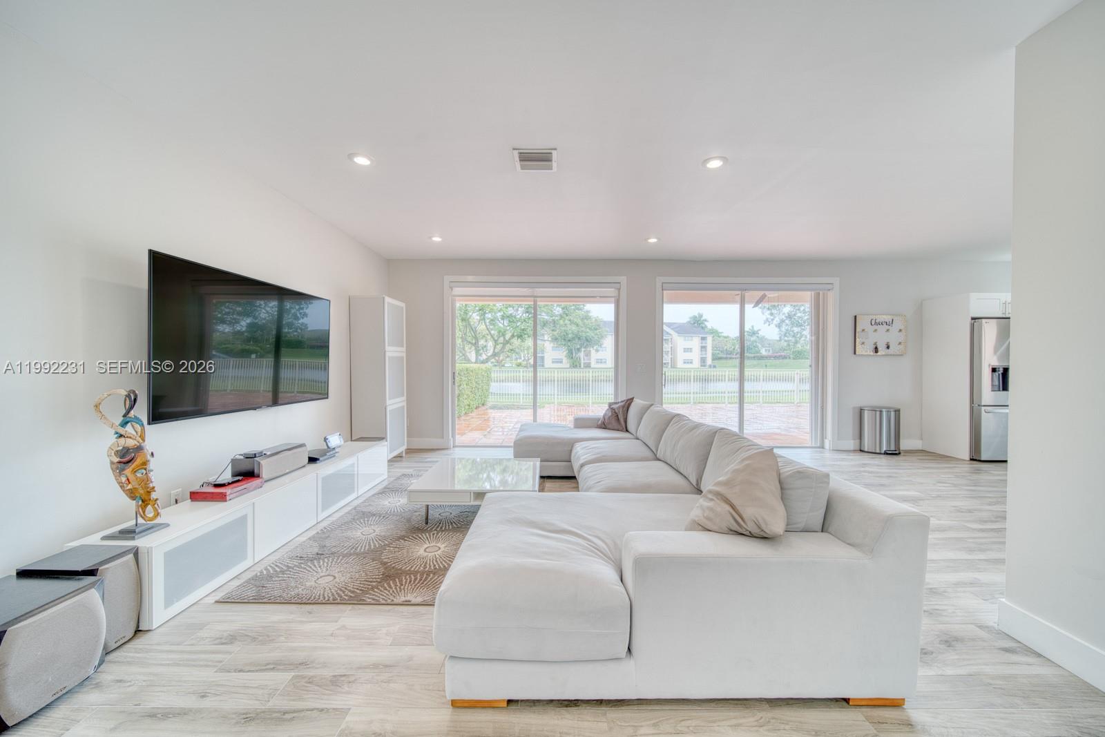 A bright living room features a large sectional sofa, white media console, and sliding glass doors — 15261 SW 108th Ter, Miami FL 33196, MIAMI, FL