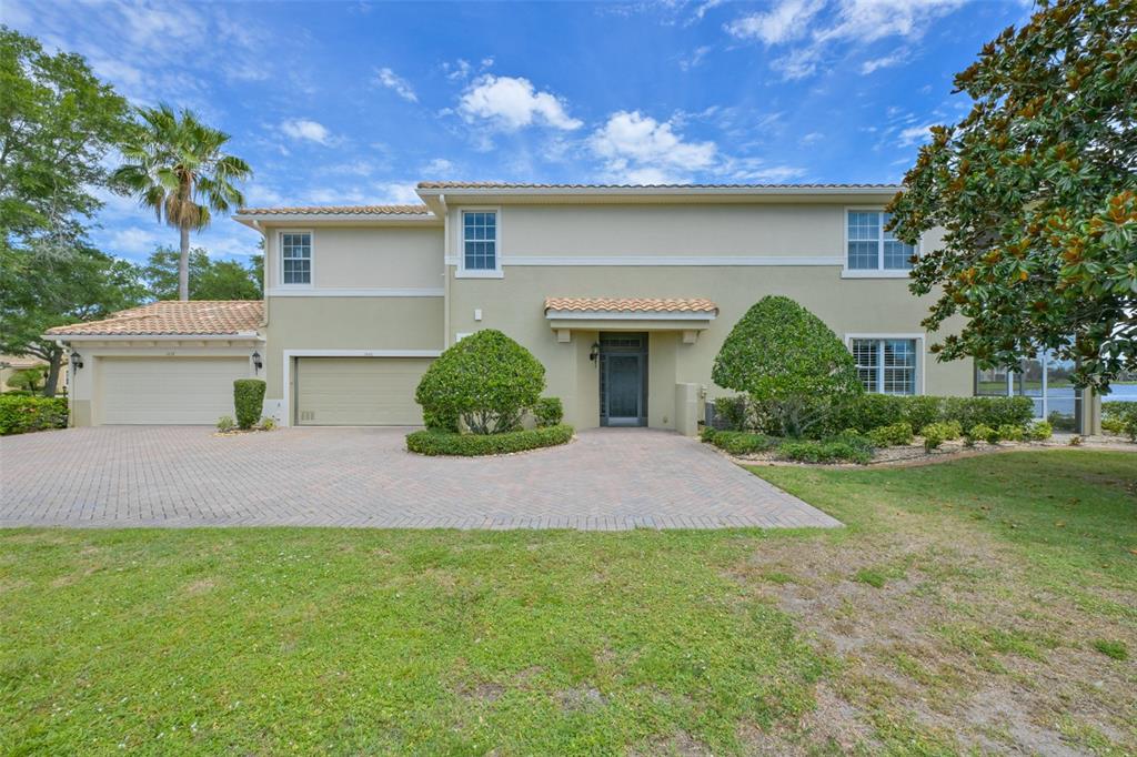 A two-story house with a beige stucco exterior, tile roof, and a paved driveway — 1440 EMERALD DUNES DRIVE, SUN CITY CENTER, FL
