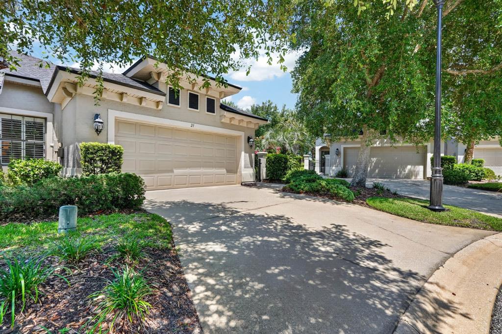 A beige house with a two-car garage and a concrete driveway under large trees — 21 RIVER LANDING DRIVE, PALM COAST, FL
