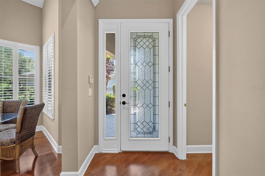 An entryway features a white front door with decorative glass, hardwood floors, and beige walls — 21 RIVER LANDING DRIVE, PALM COAST, FL