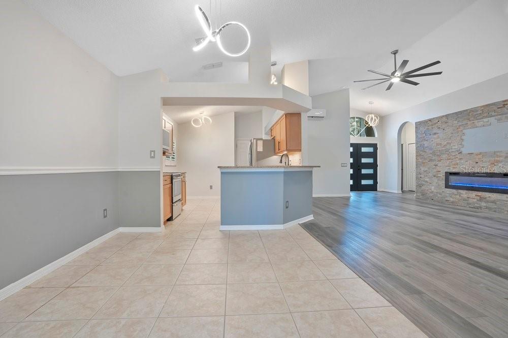 A kitchen with a breakfast bar opens into a living area with wood-look flooring — 1001 PIEDMONT OAKS DRIVE, APOPKA, FL