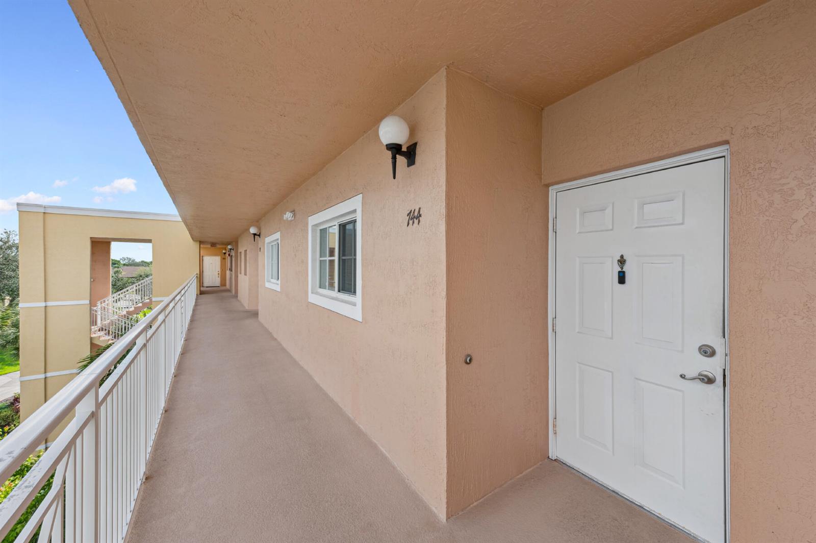 An exterior walkway leads to a white apartment door marked with the number 144 — 4721 E Lucerne Lakes Blvd E # 744, Lake Worth FL 33467, LAKE WORTH, FL