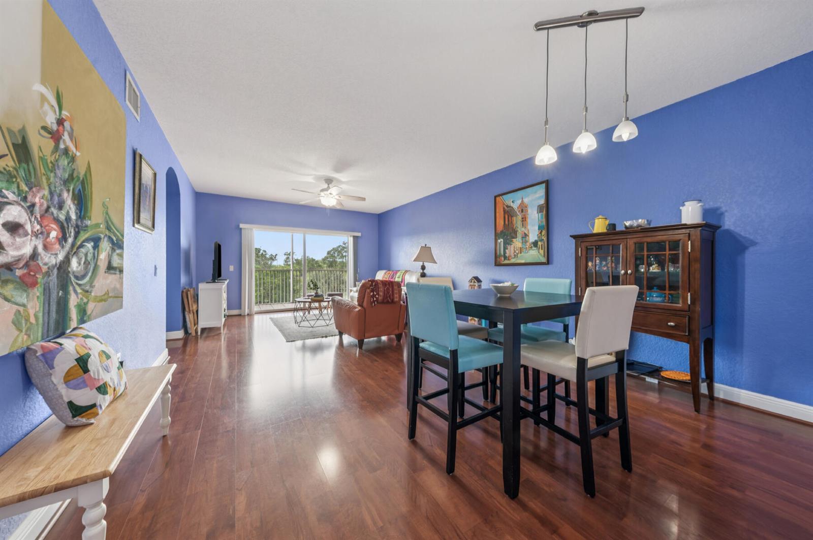 A dining area and living room with blue walls, hardwood floors, and a balcony view — 4721 E Lucerne Lakes Blvd E # 744, Lake Worth FL 33467, LAKE WORTH, FL