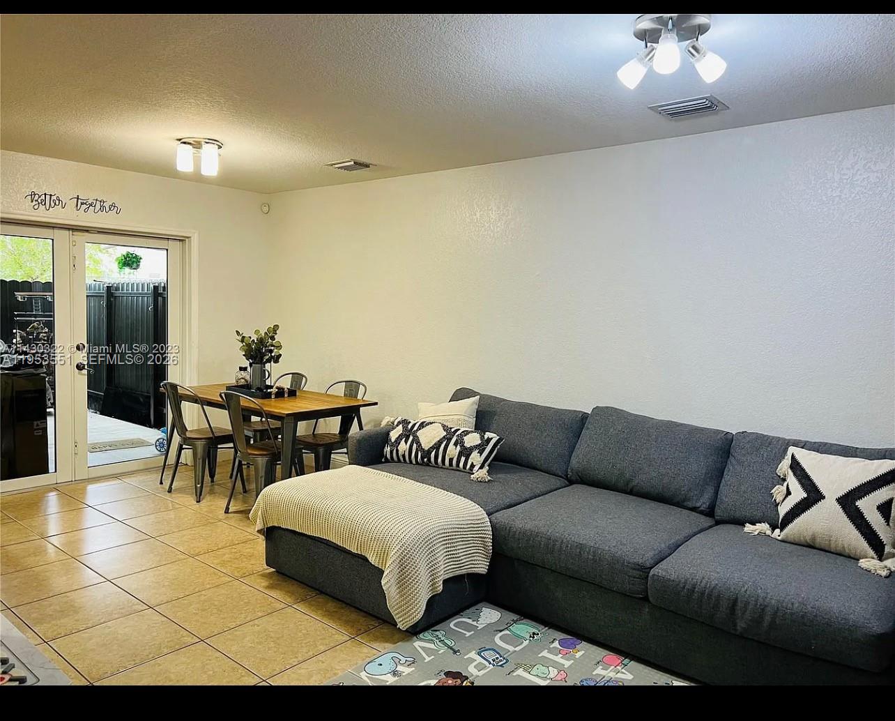 A living and dining area features tile floors, a gray sectional sofa, and glass doors — 9455 NW 114th Ln # 8, Hialeah Gardens FL 33018, HIALEAH GARDENS, FL