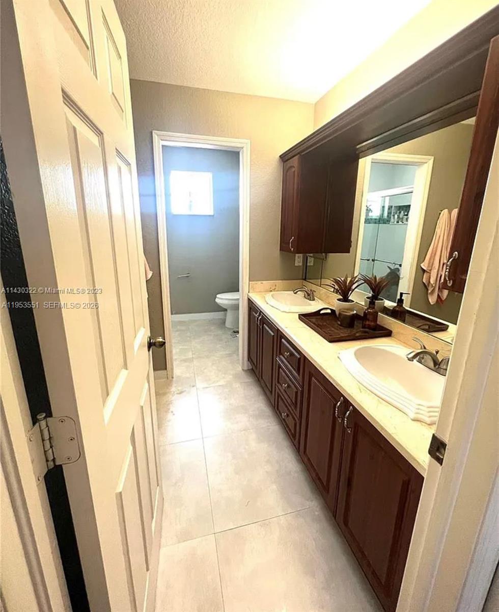 A bathroom features a double vanity with dark wood cabinets and a separate toilet area — 9455 NW 114th Ln # 8, Hialeah Gardens FL 33018, HIALEAH GARDENS, FL