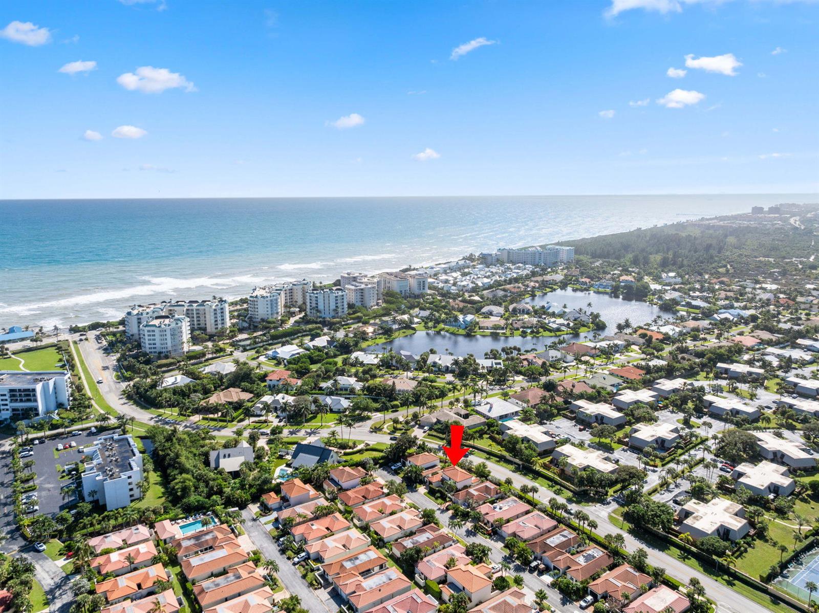 An aerial view shows a residential community with red-tiled roofs near the ocean — 1484 Via Del Sol, Jupiter FL 33477, JUPITER, FL