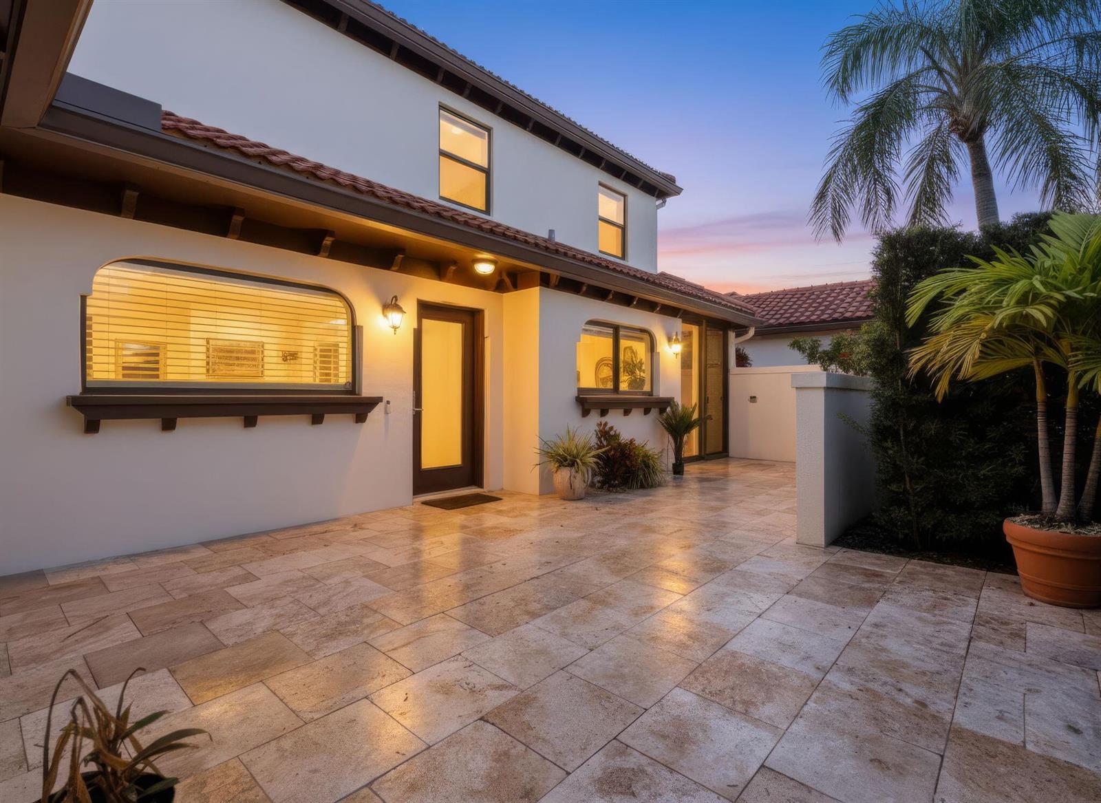 A paved patio area sits in front of a two-story house with arched windows — 1484 Via Del Sol, Jupiter FL 33477, JUPITER, FL