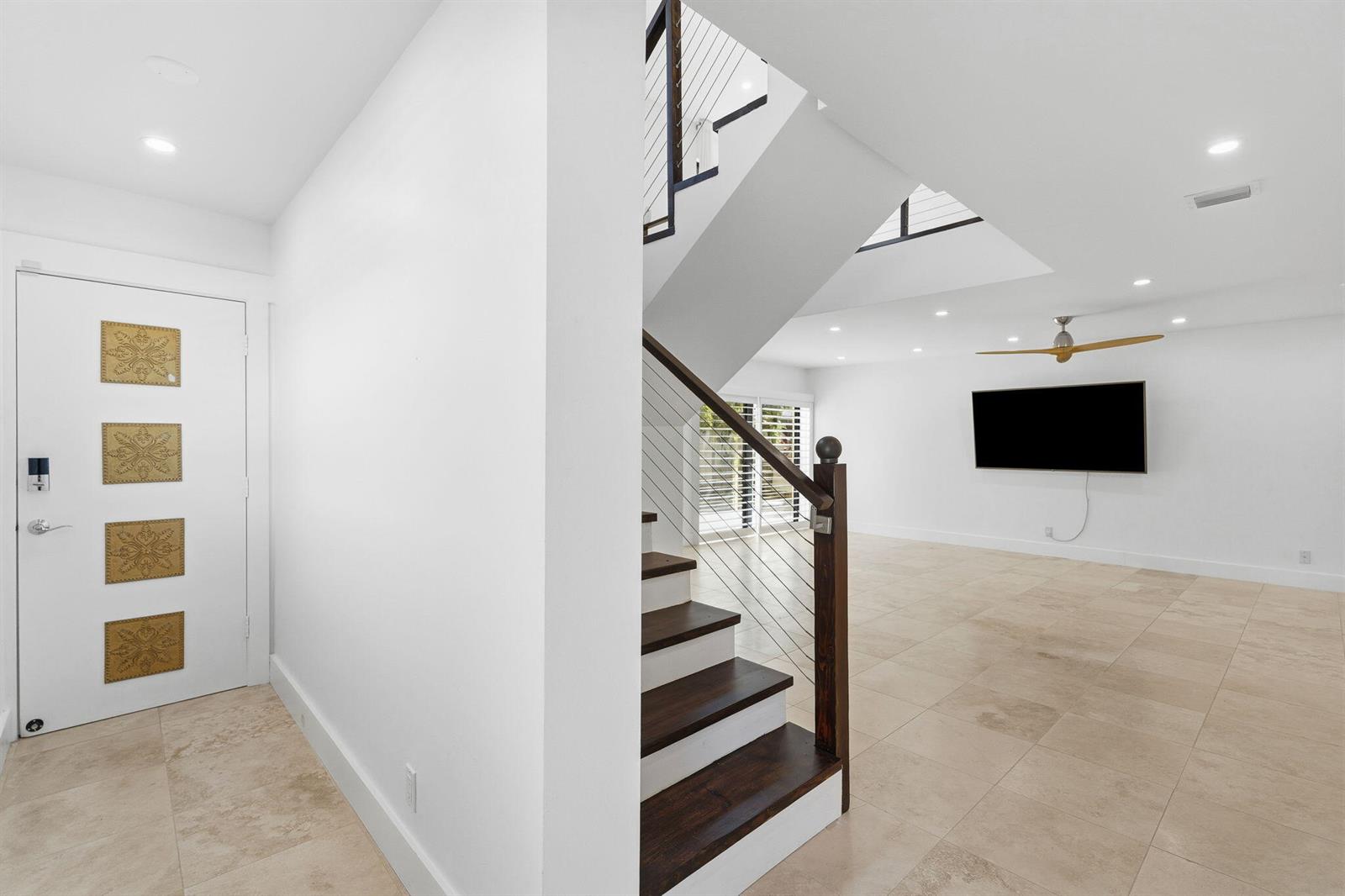 A white entryway features a modern staircase with wood treads and a cable railing system — 1484 Via Del Sol, Jupiter FL 33477, JUPITER, FL