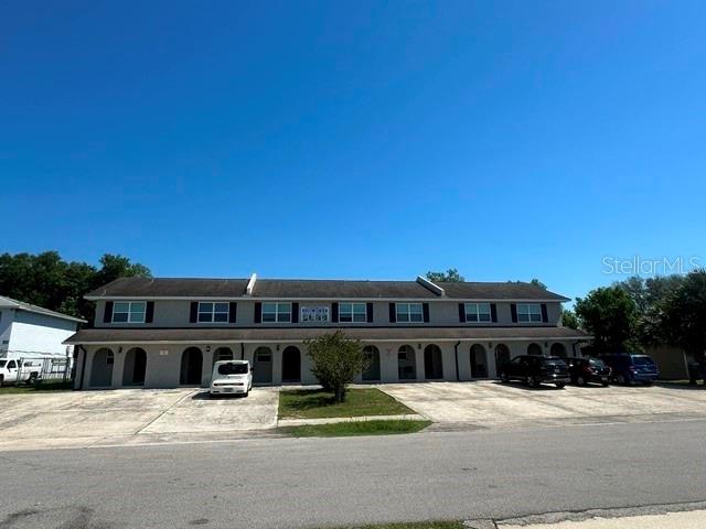 A two-story multi-family residential building features a concrete parking lot and a clear blue sky — 112 CARIBBEAN STREET, DELTONA, FL